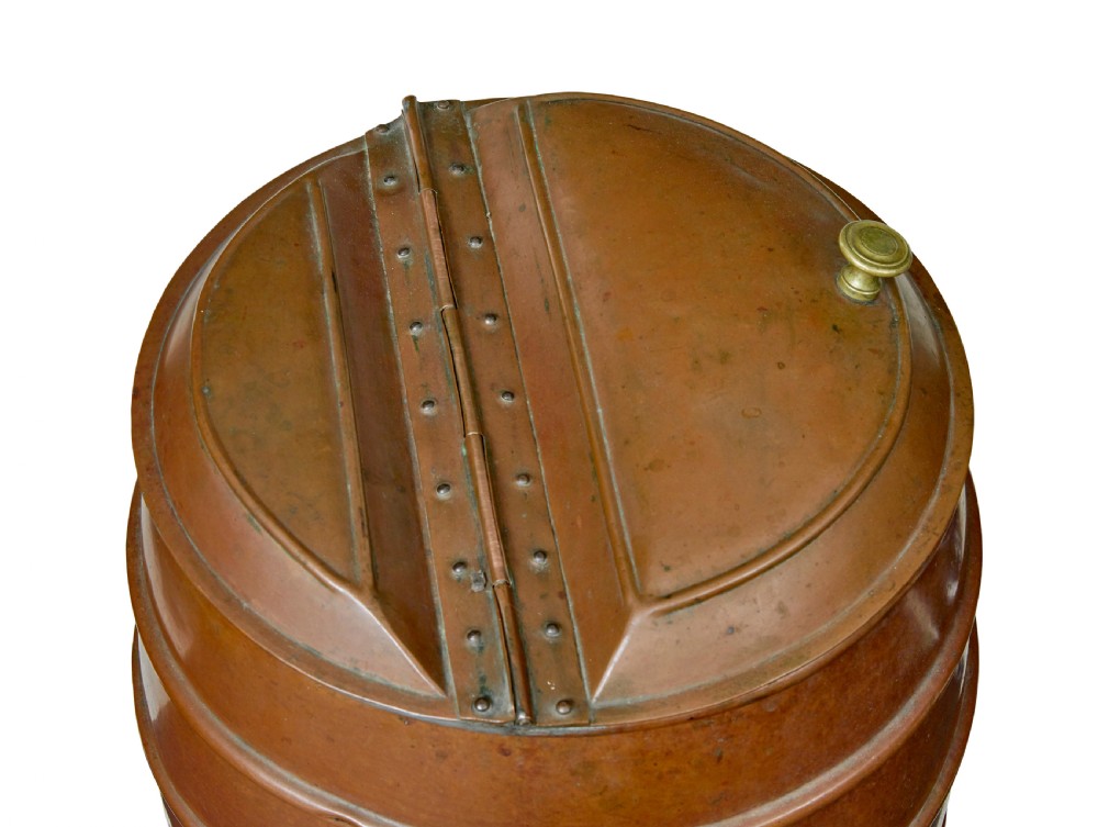 A 19th-century copper water barrel with horizontal raised bands, cast brass drop handles, a flared base, and a fitted copper lid with a brass knob. View VI