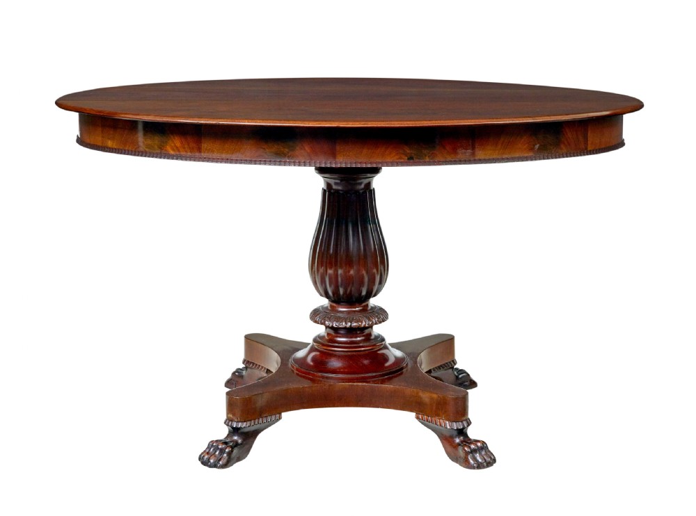 A nineteenth-century mahogany oval centre table featuring a fluted pedestal stem and carved paw feet on a concave quadripartite base.
