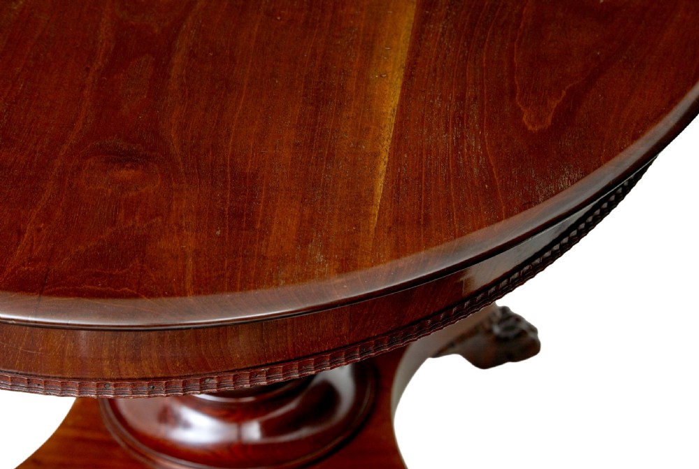 A nineteenth-century mahogany oval centre table featuring a fluted pedestal stem and carved paw feet on a concave quadripartite base. View VII