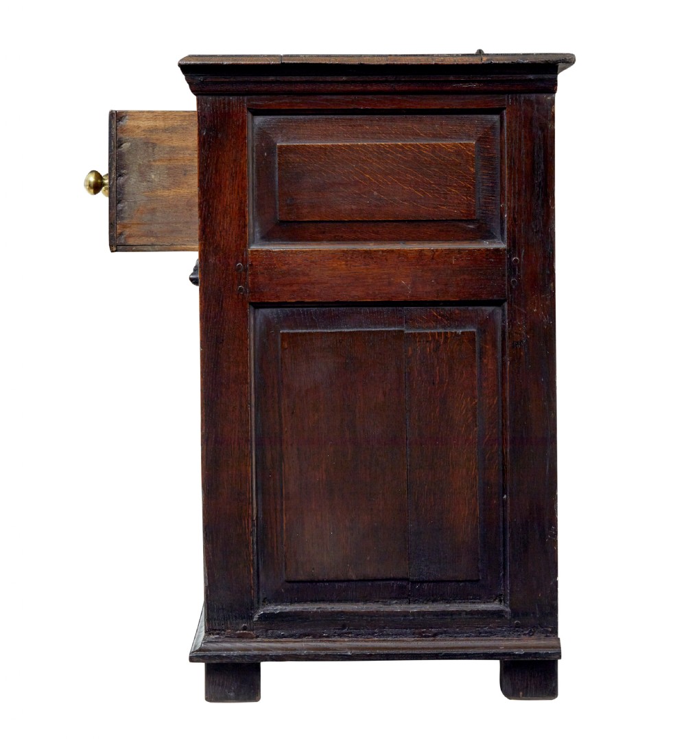 An 18th-century dark oak dresser featuring three geometric panelled drawers with brass knobs above cupboard doors with iron hinges. View VI