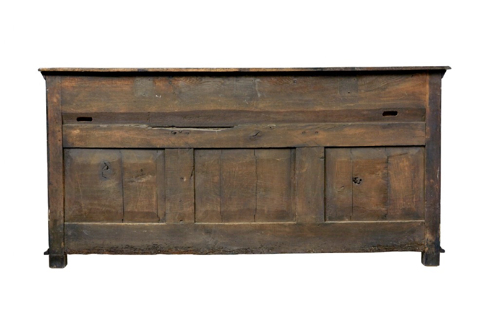 An 18th-century dark oak dresser featuring three geometric panelled drawers with brass knobs above cupboard doors with iron hinges. View VII
