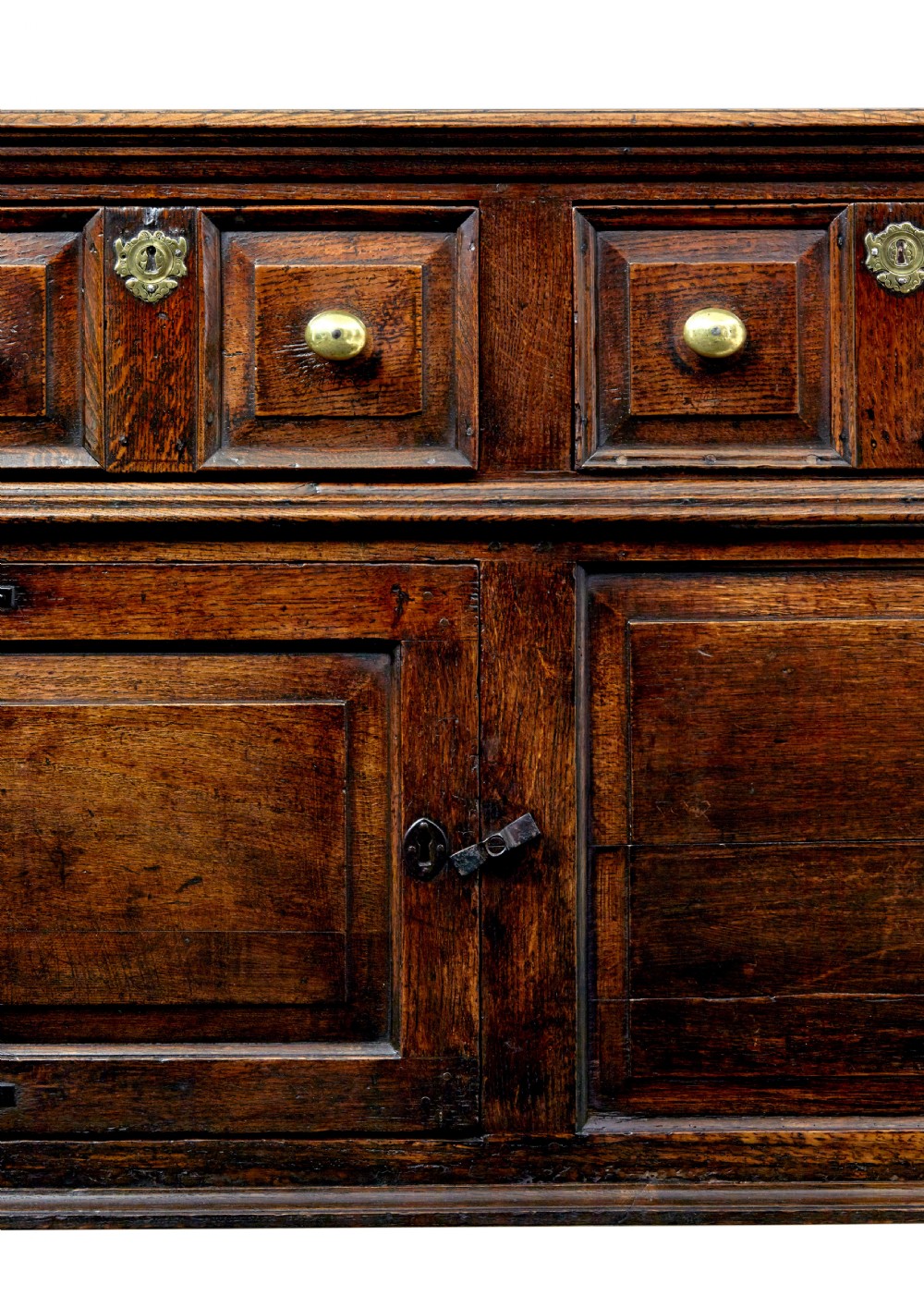 An 18th-century dark oak dresser featuring three geometric panelled drawers with brass knobs above cupboard doors with iron hinges. View IX
