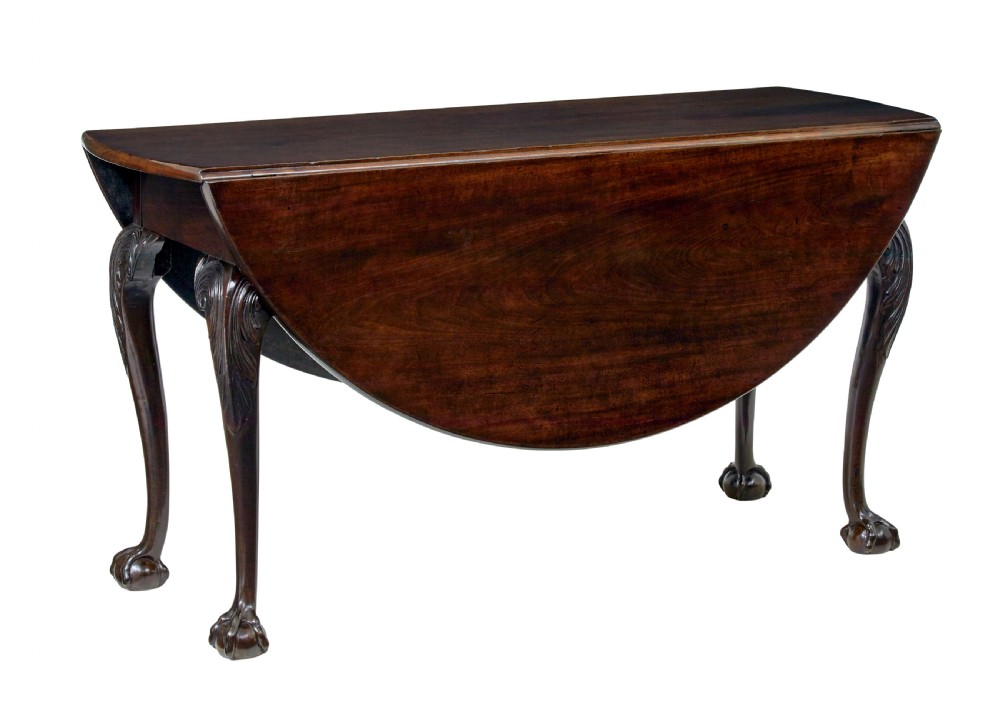 An 18th-century mahogany drop-leaf table featuring hinged oval flaps, cabriole legs with carved acanthus knees, and ball-and-claw feet.