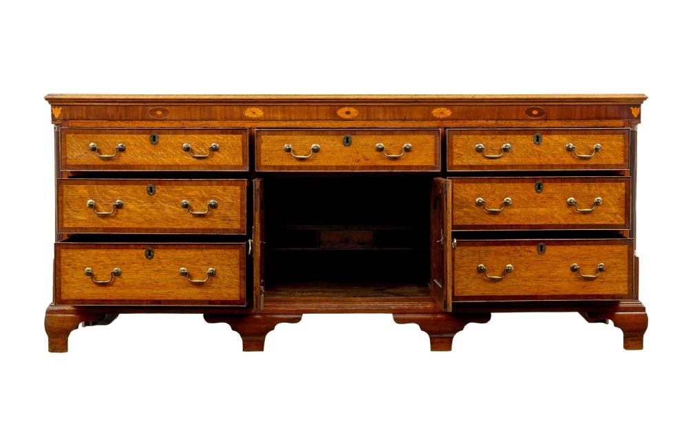 An 18th-century inlaid oak Lancashire dresser base featuring six drawers, a central two-door fielded panel cupboard, brass handles, and ogee bracket feet. View III