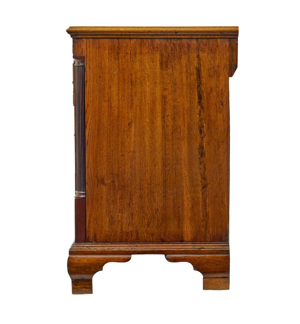 An 18th-century inlaid oak Lancashire dresser base featuring six drawers, a central two-door fielded panel cupboard, brass handles, and ogee bracket feet. View VI