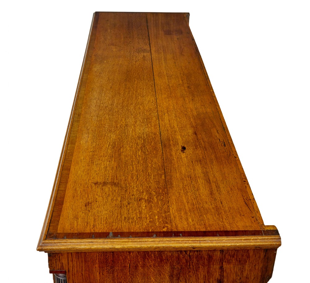 An 18th-century inlaid oak Lancashire dresser base featuring six drawers, a central two-door fielded panel cupboard, brass handles, and ogee bracket feet. View XII