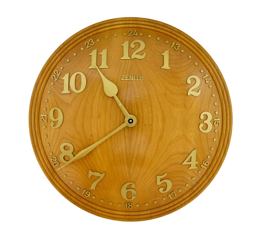A circular Art Deco wall clock crafted from warm brown elm wood with applied brass numerals and hands.