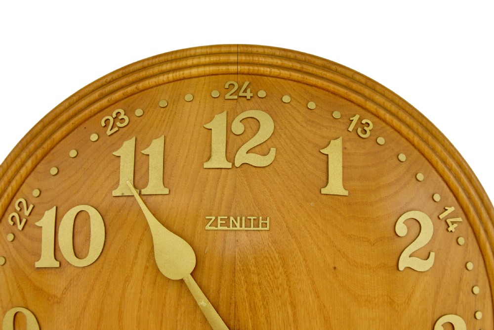 A circular Art Deco wall clock crafted from warm brown elm wood with applied brass numerals and hands. View II