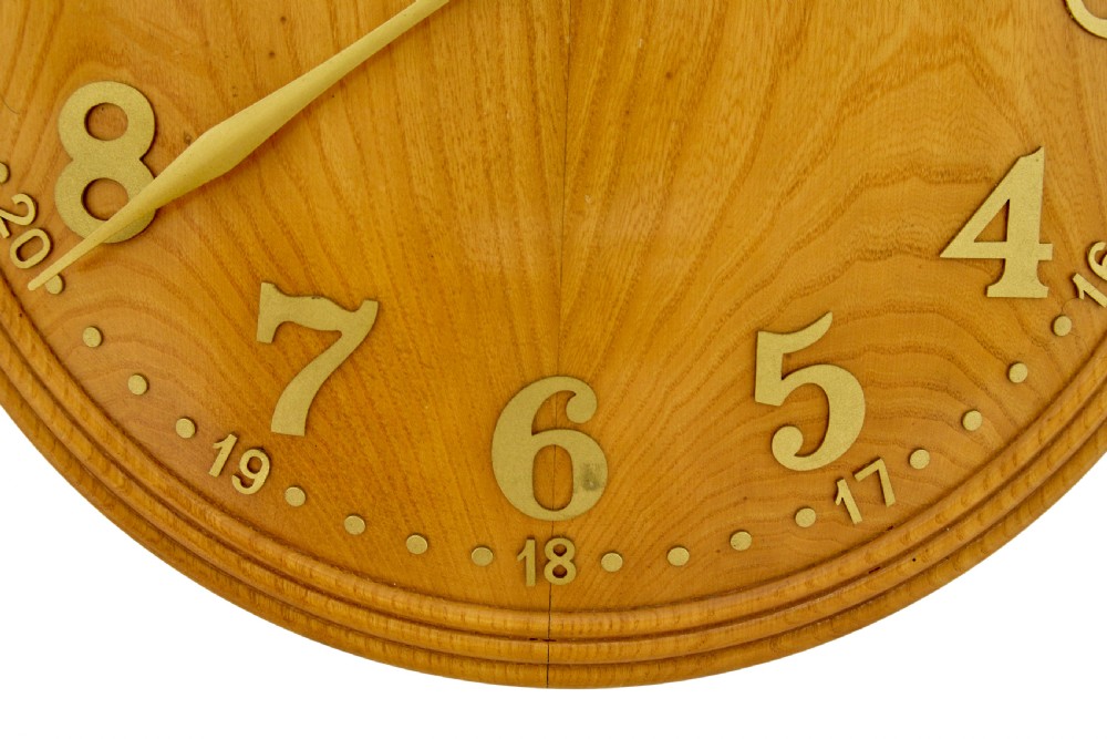 A circular Art Deco wall clock crafted from warm brown elm wood with applied brass numerals and hands. View III
