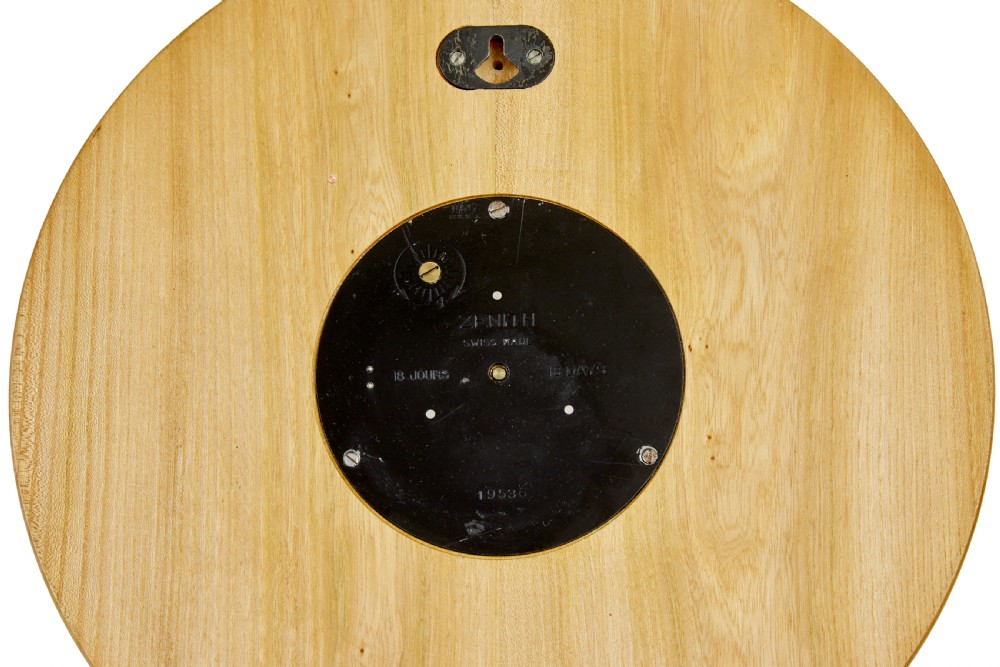 A circular Art Deco wall clock crafted from warm brown elm wood with applied brass numerals and hands. View V