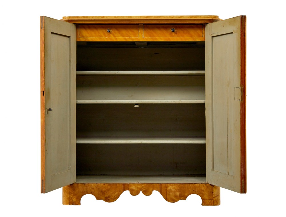 A nineteenth-century Swedish satin birch cupboard featuring two panelled doors with keyhole escutcheons and a shaped scalloped apron base. View III