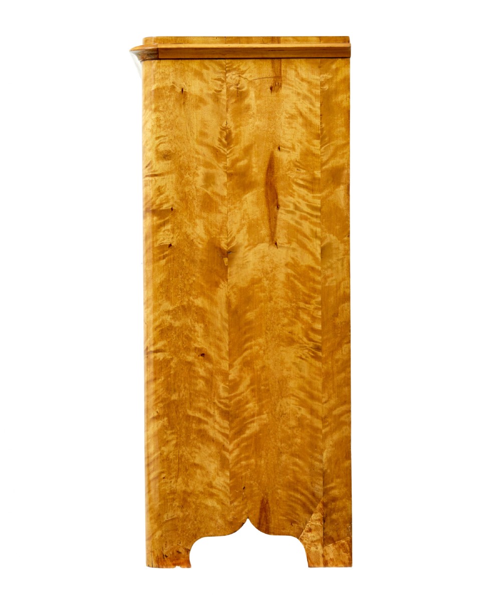 A nineteenth-century Swedish satin birch cupboard featuring two panelled doors with keyhole escutcheons and a shaped scalloped apron base. View V
