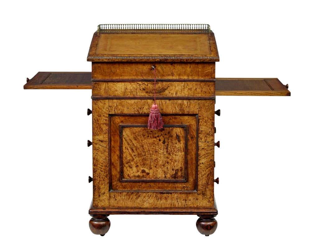 A mid-nineteenth century pollard oak Davenport desk featuring a sloped leather writing top with a brass gallery rail, side drawers with wooden knobs, and turned feet. View II