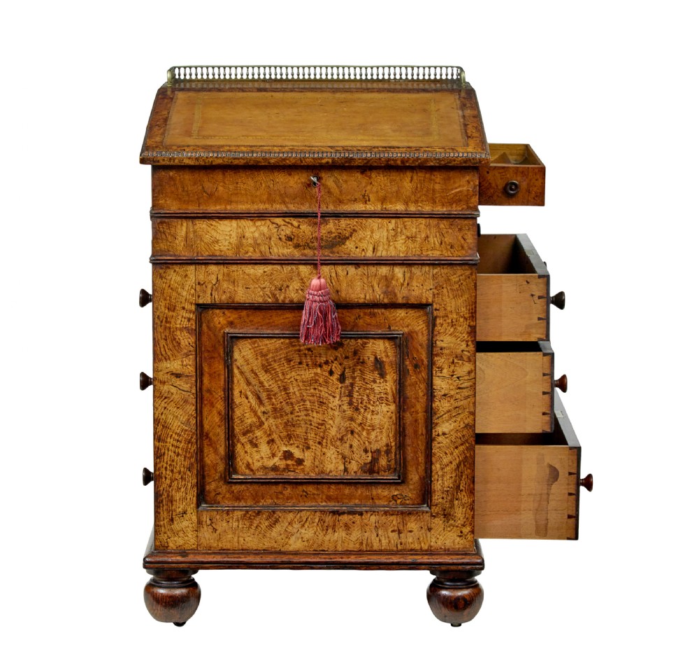 A mid-nineteenth century pollard oak Davenport desk featuring a sloped leather writing top with a brass gallery rail, side drawers with wooden knobs, and turned feet. View III