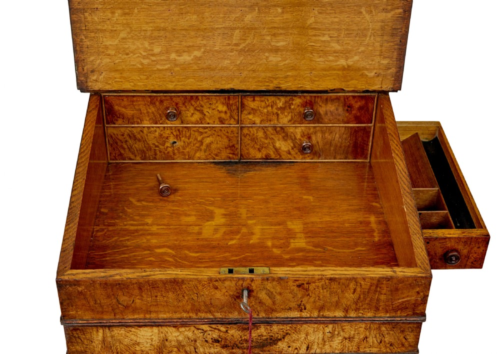 A mid-nineteenth century pollard oak Davenport desk featuring a sloped leather writing top with a brass gallery rail, side drawers with wooden knobs, and turned feet. View XI