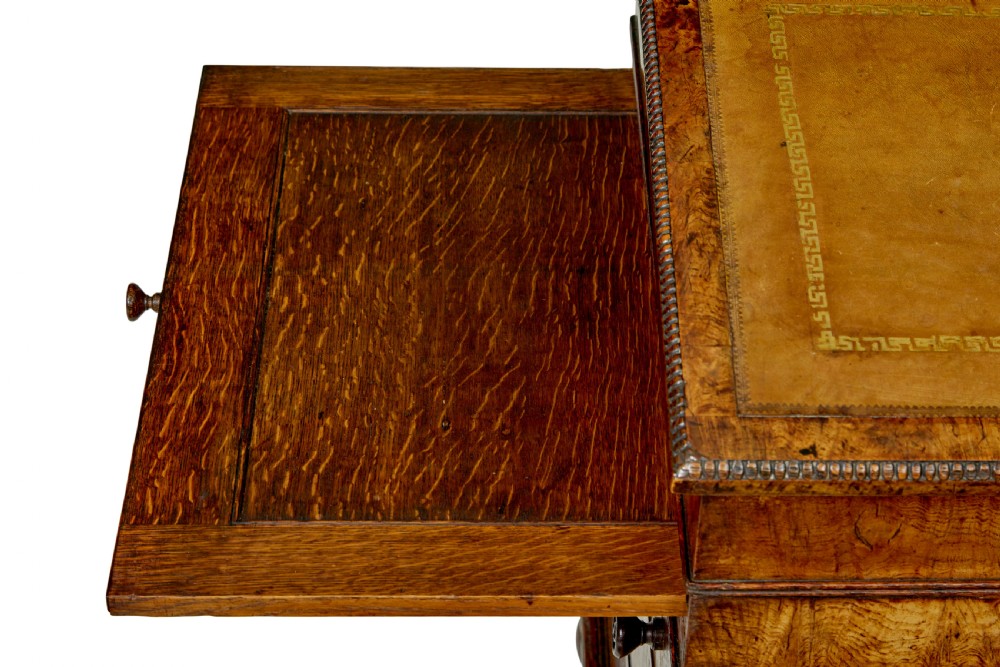 A mid-nineteenth century pollard oak Davenport desk featuring a sloped leather writing top with a brass gallery rail, side drawers with wooden knobs, and turned feet. View XIII