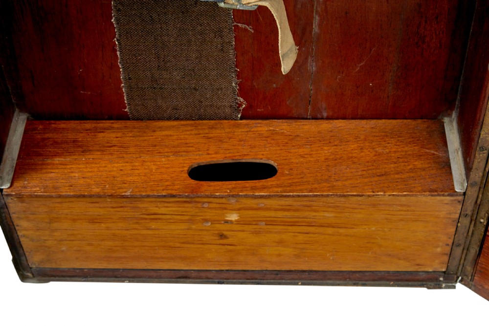 An open early 20th-century vertical steamer chest featuring a clothes hanging compartment with straps on the left and a column of six wooden drawers with recessed brass handles on the right. View XI