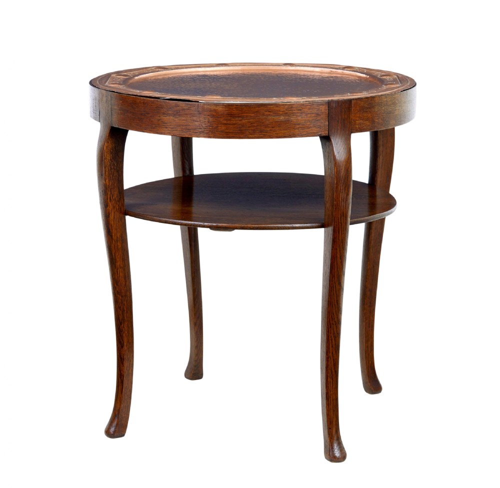 A late 19th-century Arts and Crafts circular oak occasional table featuring a central inset hammered copper tray top and a lower circular tier.