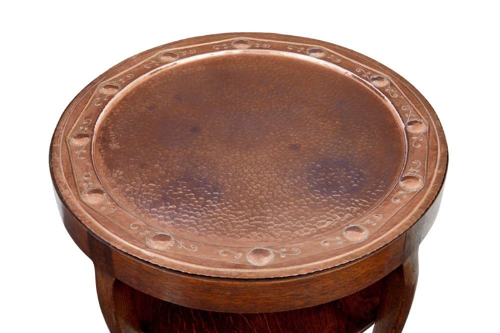 A late 19th-century Arts and Crafts circular oak occasional table featuring a central inset hammered copper tray top and a lower circular tier. View V