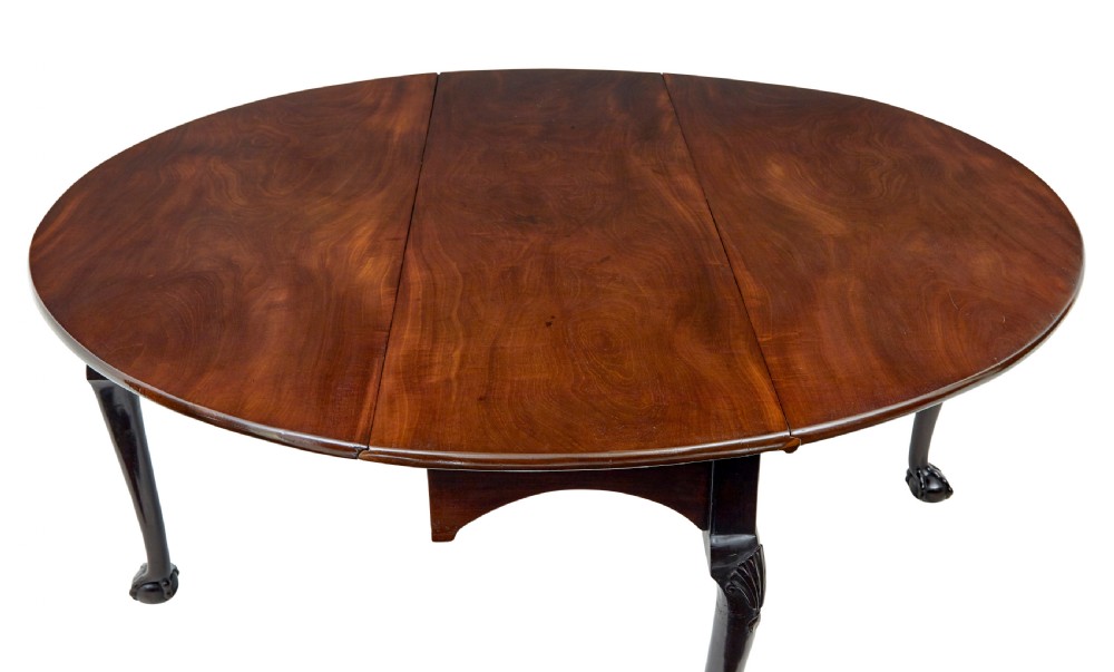 An eighteenth-century dark mahogany oval drop-leaf dining table featuring cabriole legs with carved knees and claw-and-ball feet. View II