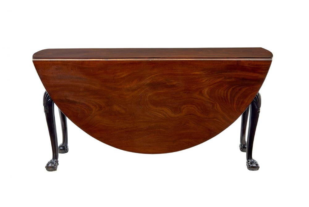 An eighteenth-century dark mahogany oval drop-leaf dining table featuring cabriole legs with carved knees and claw-and-ball feet. View V