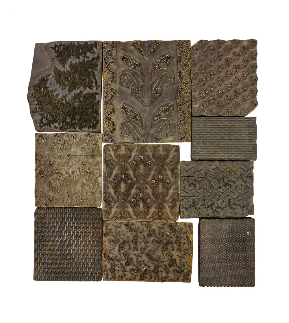 A collection of ten square and rectangular hand-carved wooden textile printing blocks featuring intricate brass wire and pin patterns.
