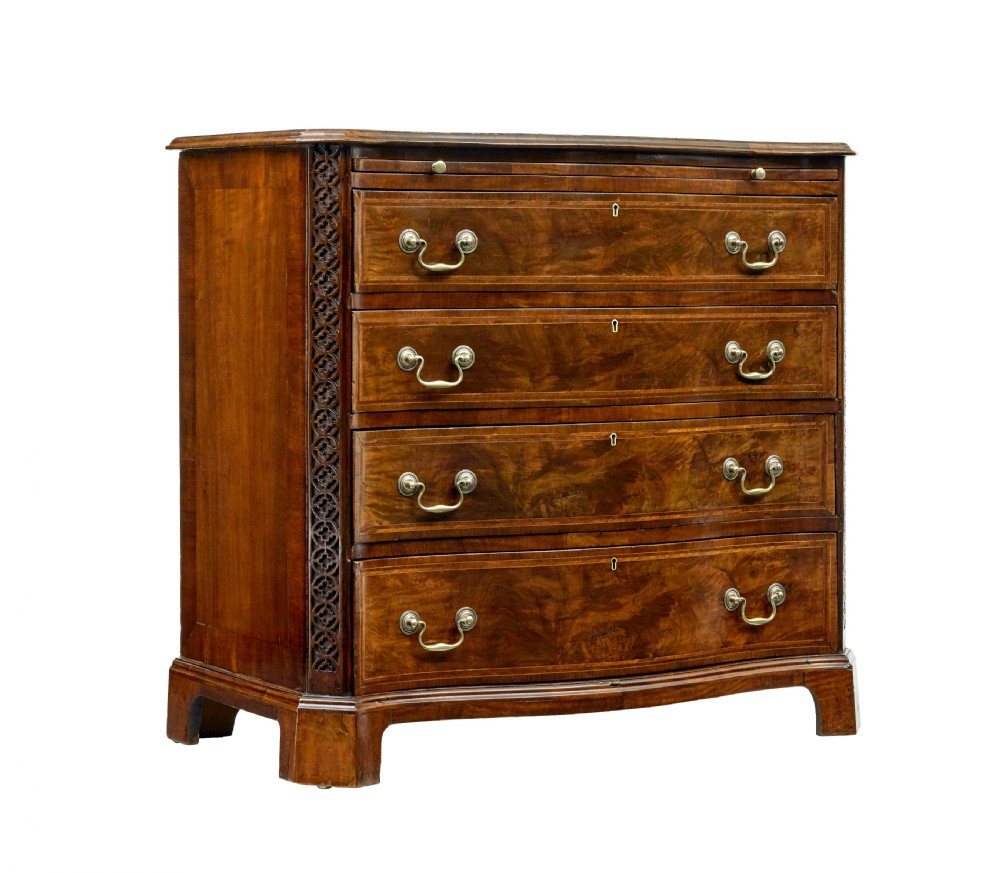 An early 19th-century walnut chest of drawers featuring four graduating drawers with brass handles, carved fretwork corners, and bracket feet.
