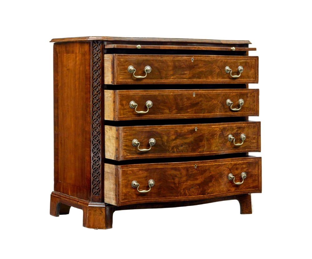 An early 19th-century walnut chest of drawers featuring four graduating drawers with brass handles, carved fretwork corners, and bracket feet. View II