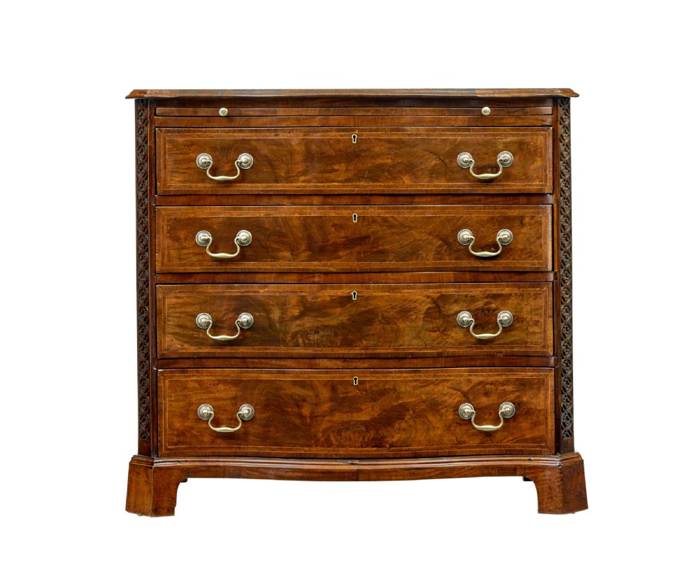An early 19th-century walnut chest of drawers featuring four graduating drawers with brass handles, carved fretwork corners, and bracket feet. View III