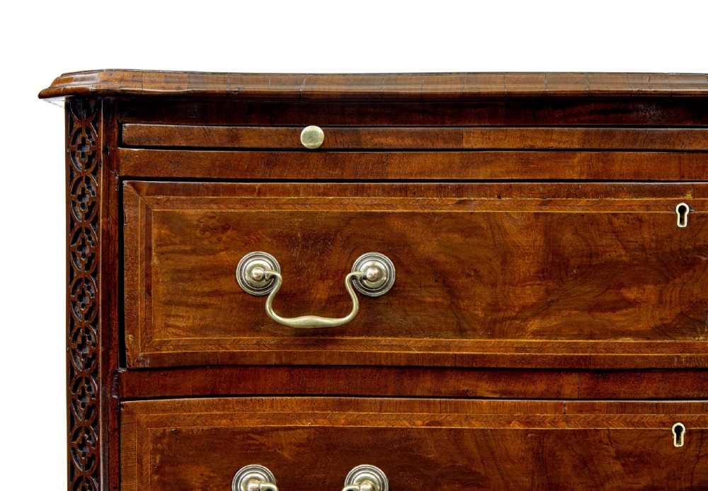 An early 19th-century walnut chest of drawers featuring four graduating drawers with brass handles, carved fretwork corners, and bracket feet. View VIII
