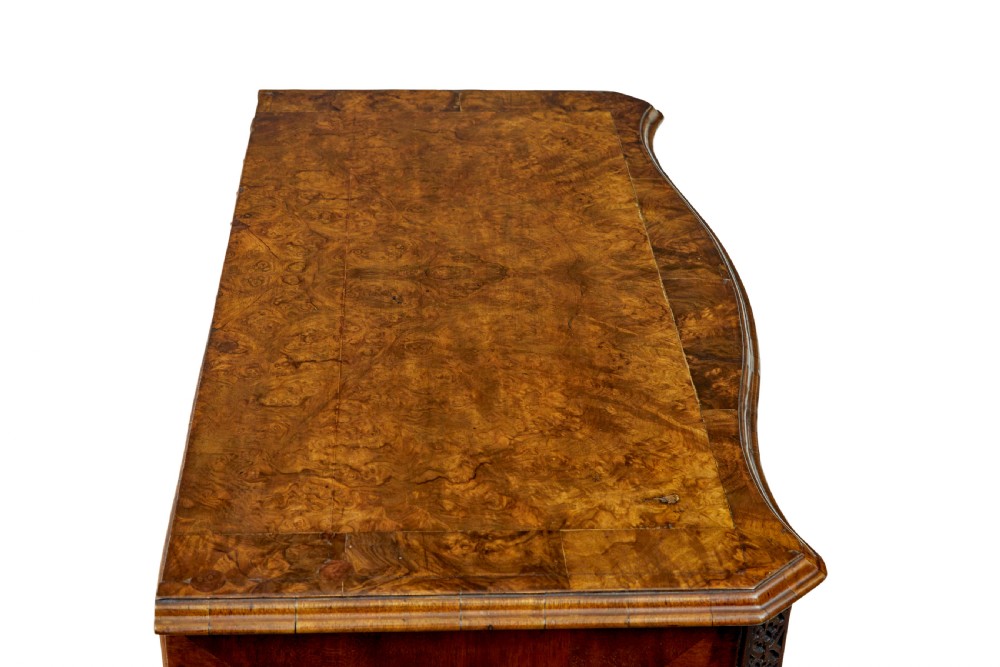 An early 19th-century walnut chest of drawers featuring four graduating drawers with brass handles, carved fretwork corners, and bracket feet. View IX