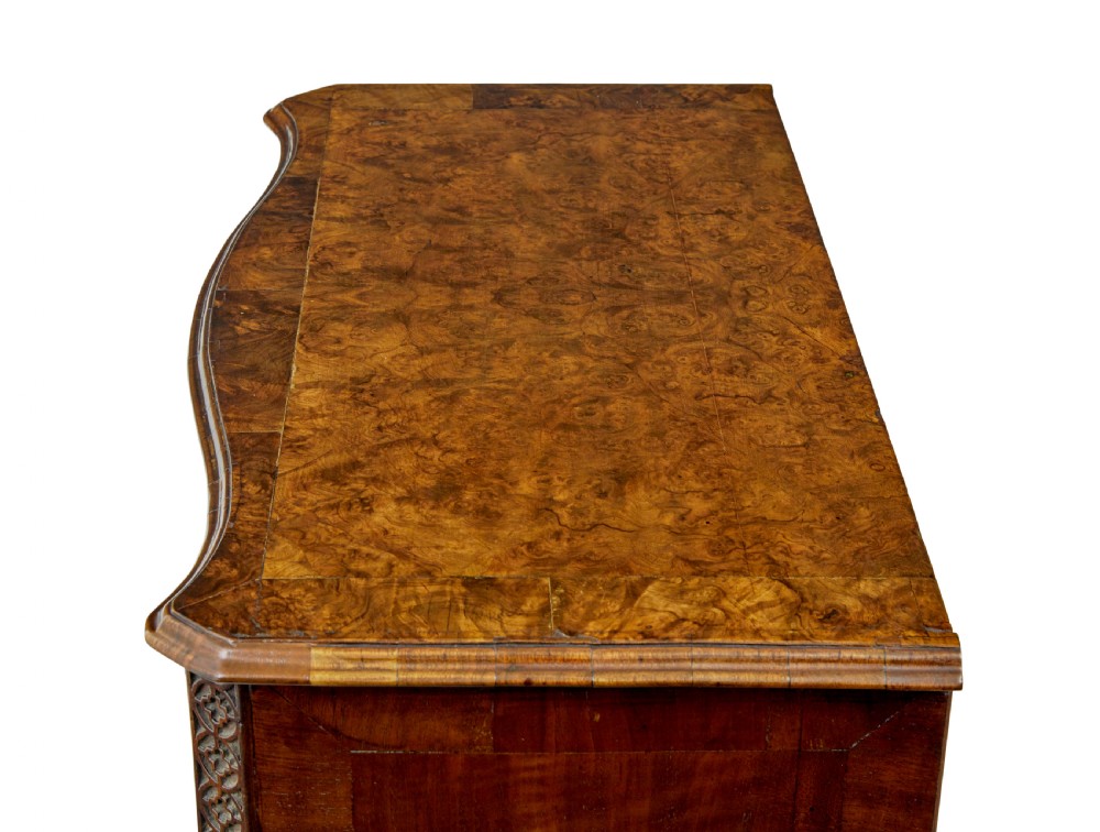 An early 19th-century walnut chest of drawers featuring four graduating drawers with brass handles, carved fretwork corners, and bracket feet. View XI