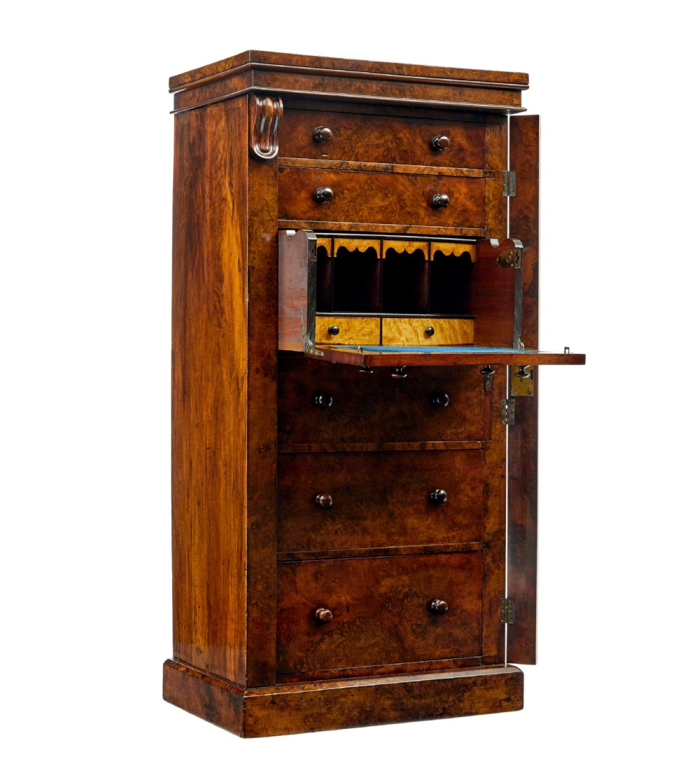 A tall, narrow Victorian burr walnut Wellington chest featuring seven graduated drawers with turned knob handles, decorative scroll brackets, and a locking side pilaster set upon a plinth base. View II