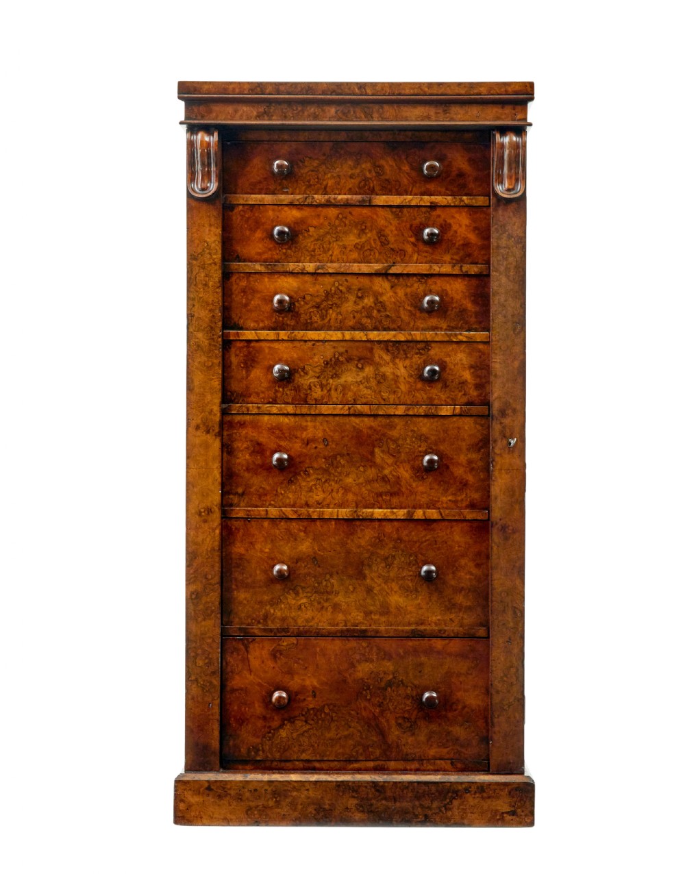 A tall, narrow Victorian burr walnut Wellington chest featuring seven graduated drawers with turned knob handles, decorative scroll brackets, and a locking side pilaster set upon a plinth base. View IV