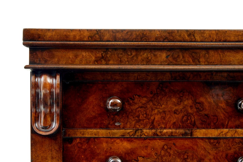 A tall, narrow Victorian burr walnut Wellington chest featuring seven graduated drawers with turned knob handles, decorative scroll brackets, and a locking side pilaster set upon a plinth base. View VIII
