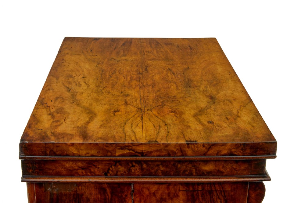 A tall, narrow Victorian burr walnut Wellington chest featuring seven graduated drawers with turned knob handles, decorative scroll brackets, and a locking side pilaster set upon a plinth base. View XI