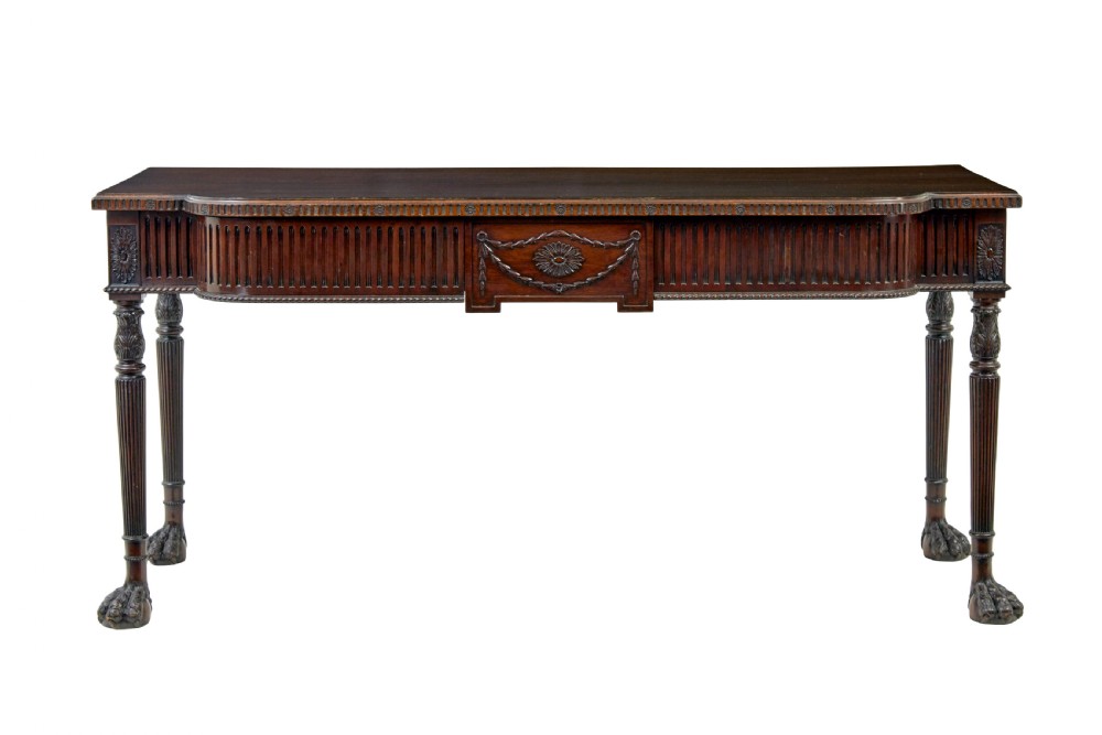 A nineteenth-century dark mahogany Irish serving table featuring a reeded frieze, central drawer with carved swag motif, and fluted legs with carved feet. View II