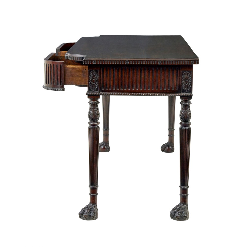 A nineteenth-century dark mahogany Irish serving table featuring a reeded frieze, central drawer with carved swag motif, and fluted legs with carved feet. View IV