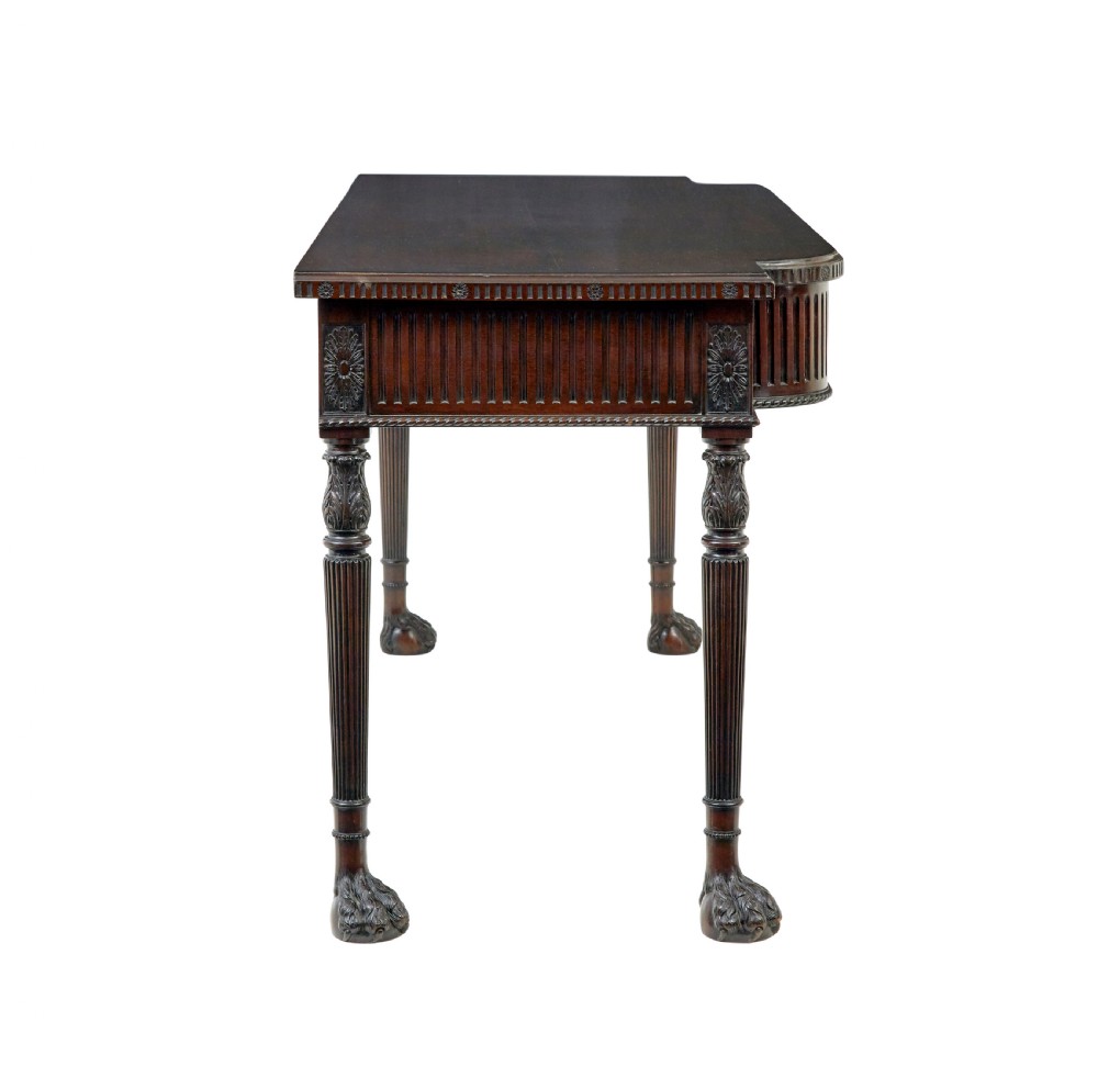 A nineteenth-century dark mahogany Irish serving table featuring a reeded frieze, central drawer with carved swag motif, and fluted legs with carved feet. View VI