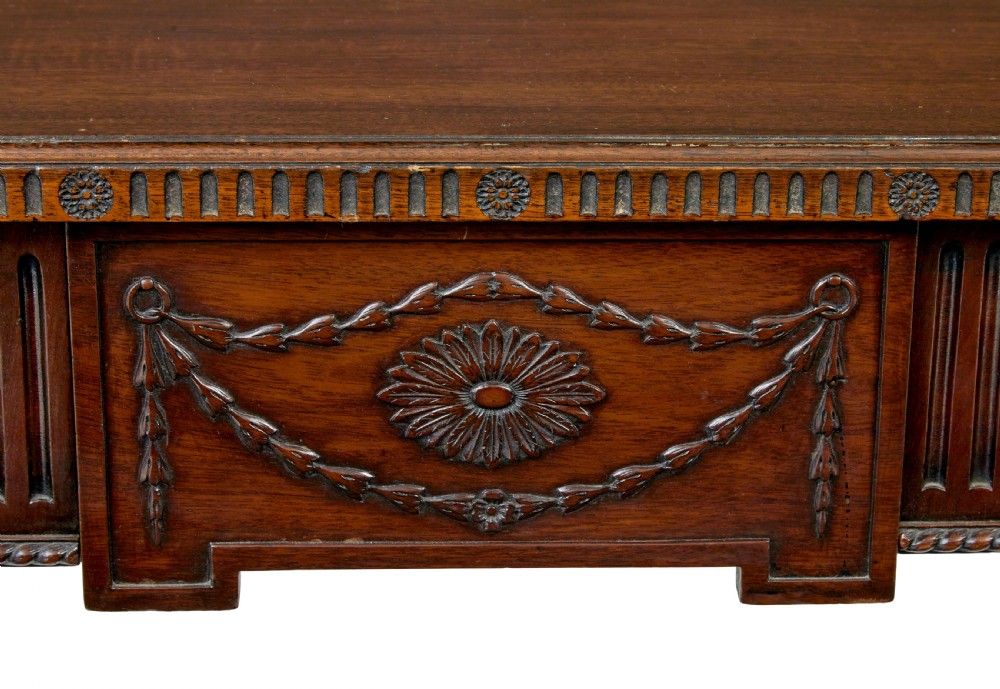 A nineteenth-century dark mahogany Irish serving table featuring a reeded frieze, central drawer with carved swag motif, and fluted legs with carved feet. View VIII
