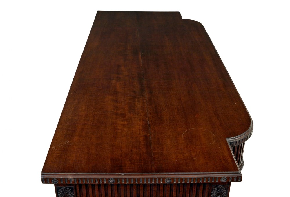 A nineteenth-century dark mahogany Irish serving table featuring a reeded frieze, central drawer with carved swag motif, and fluted legs with carved feet. View X