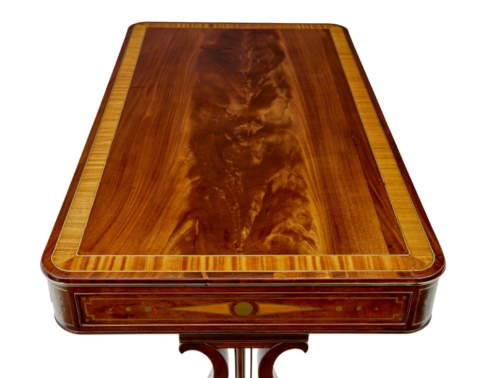 A 19th-century Regency writing desk featuring brass inlay, two frieze drawers, lyre-shaped end supports, and brass paw feet on castors. View II