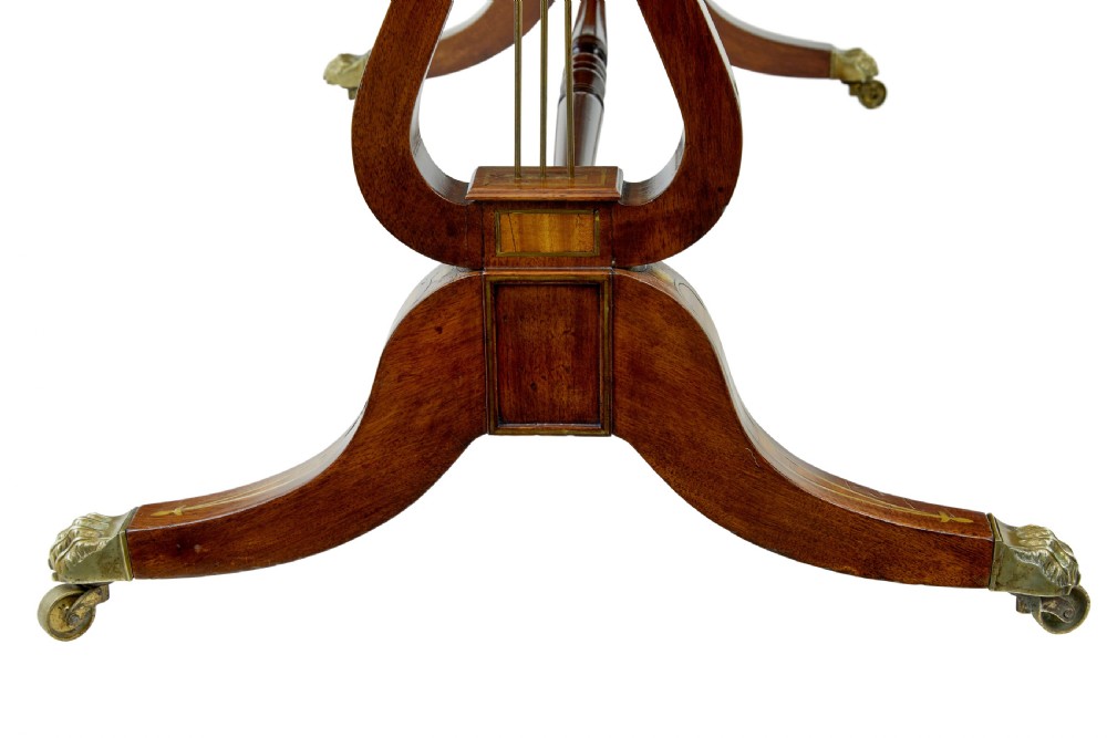 A 19th-century Regency writing desk featuring brass inlay, two frieze drawers, lyre-shaped end supports, and brass paw feet on castors. View V