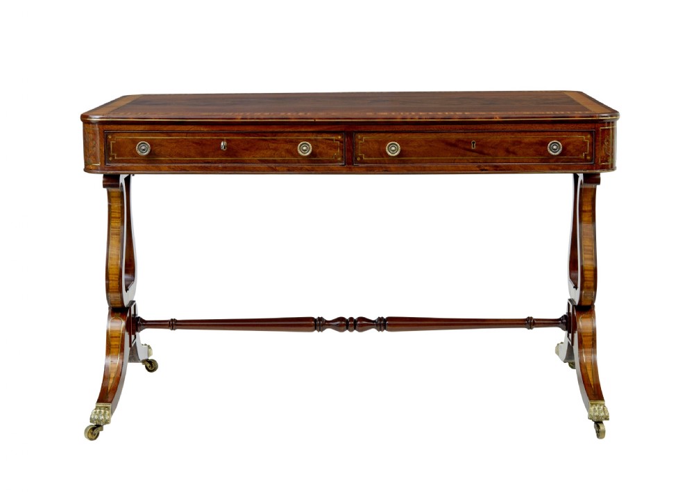 A 19th-century Regency writing desk featuring brass inlay, two frieze drawers, lyre-shaped end supports, and brass paw feet on castors. View VIII