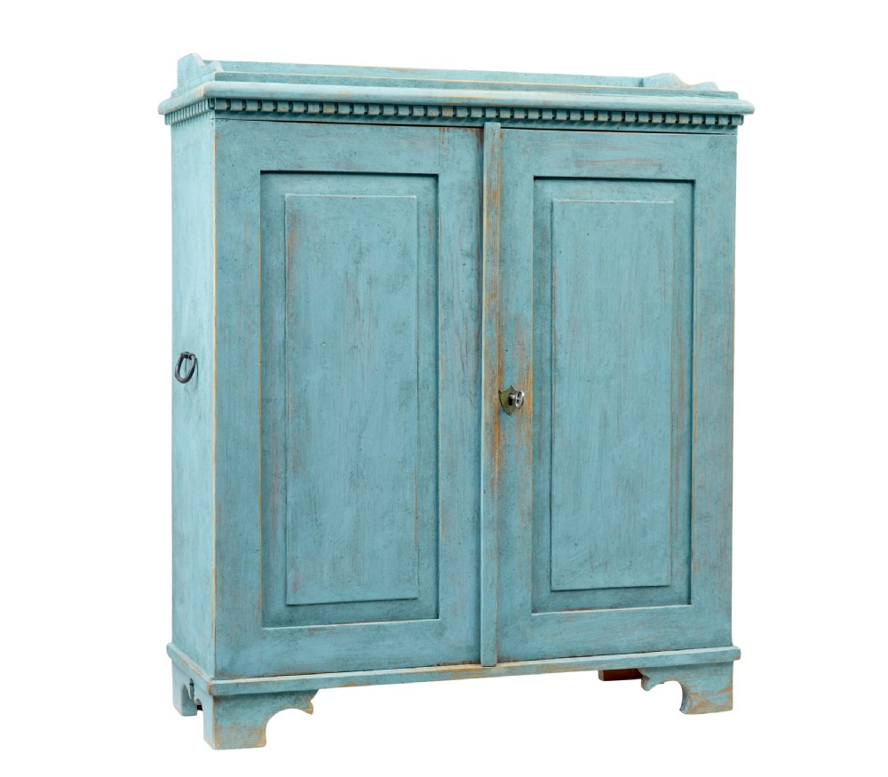 A 19th-century Scandinavian pine double-door cupboard with a distressed light blue painted finish, dentil moulding along the top, and cut-out bracket feet.
