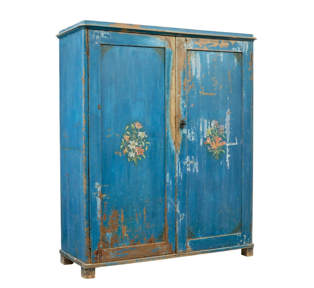 A mid-19th-century Scandinavian pine cupboard featuring distressed blue paint, two panelled doors with painted floral motifs, and short block feet.