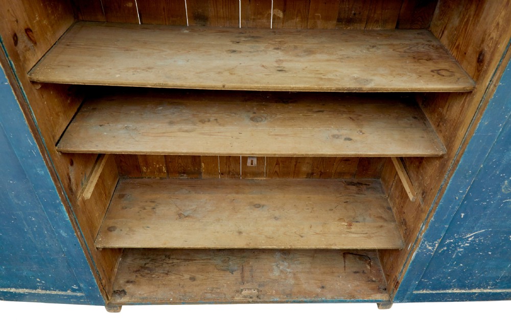 A mid-19th-century Scandinavian pine cupboard featuring distressed blue paint, two panelled doors with painted floral motifs, and short block feet. View VIII