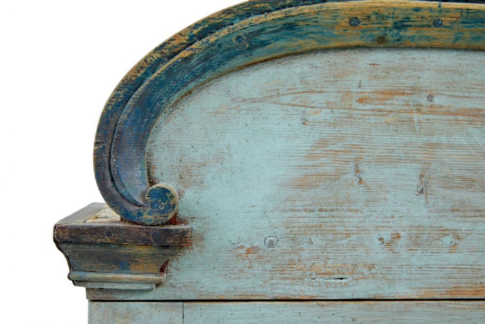 A 19th-century Finnish painted pine wall cupboard featuring weathered light blue paint, an arched pediment crest, and a door panel carved with a diamond pattern. View VII