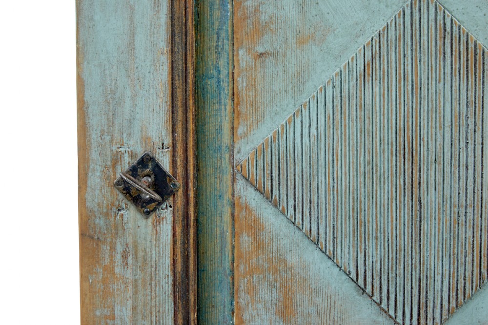 A 19th-century Finnish painted pine wall cupboard featuring weathered light blue paint, an arched pediment crest, and a door panel carved with a diamond pattern. View VIII