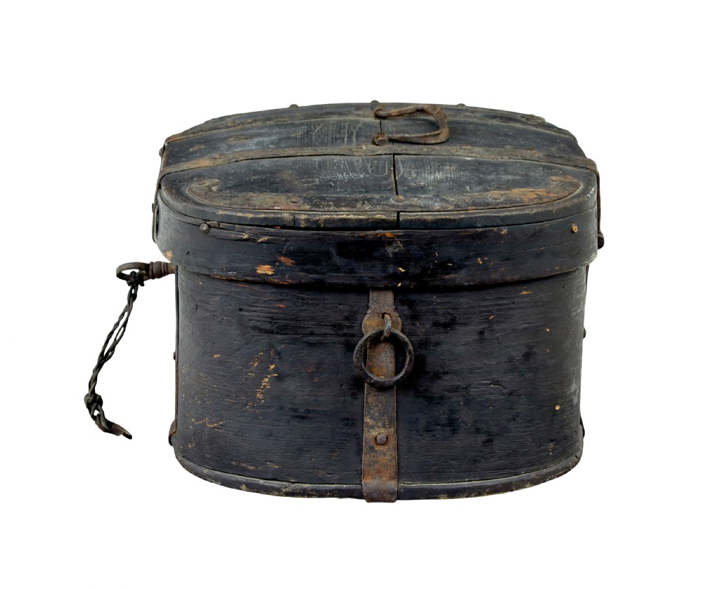 An oval 19th-century Swedish black painted wooden box featuring hand-forged iron straps, side carrying rings, and a key inserted into the central escutcheon. View II